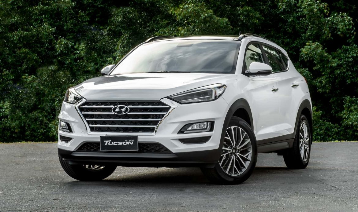 Face avant du Hyundai Tucson devant une haie de buisson, mettant en valeur son design moderne